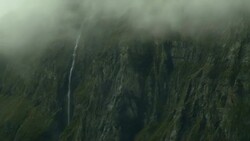 A high waterfall spills over a foggy cliff. Stock Footage