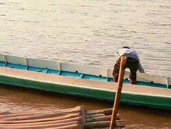 MS PAN Shot of boy using river water to clean canoe / Luang Prabang, Laos Stock Footage