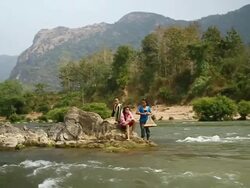 MS POV SLO MO Shot of Travelling boat three girls standing on rocks in middle of river looking at towards at beginning / Ou river, Luang Prabang, Laos Stock Footage