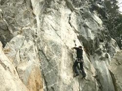 A Japanese rock climber climbs up a large crack in the rock face Stock Footage