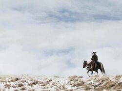 WS Cowboy riding horse along snowy ridge / Shell, Wyoming, United States Stock Footage
