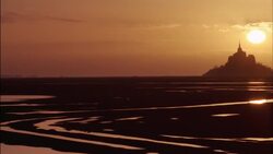 The sun silhouettes Mt. St Michel in Normandy, France. Stock Footage