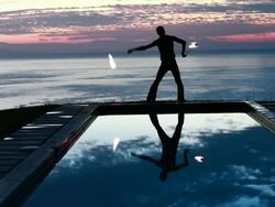 WS Male poi dancer performing with fireballs in front of pool with reflection of his silhouette in pool at sunrise / Montezuma, Costa Rica Stock Footage