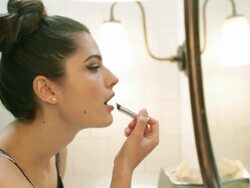 Young woman applying lipstick in bathroom mirror Stock Footage