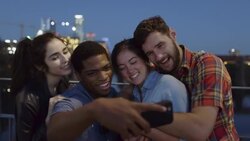 Group of friends take selfie together on pedestrian bridge overlooking Colorado River at night Stock Footage