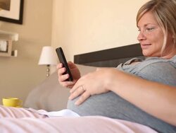 A young women using a technological device while pregnant. Stock Footage