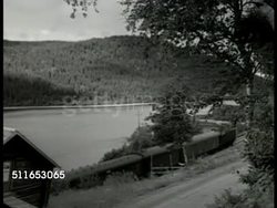 1949: SWEDEN LIFESTYLE: HA XWS Swedish country side. HA WS Train moving alongside lake, mountains BG. MS Town water fountain & horse & rider statue, crowded market place BG. MS Woman buying wurst. LA WS Church tower. Instructional Video