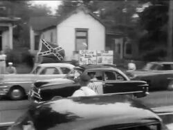 B/W 1950s PAN car with Confederate flag + KKK sign driving past desgregated school / newsreel Stock Footage