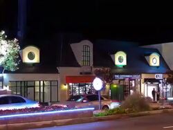 WS T/L stores at Sunset Plaza on the Sunset Strip at night with roving search lights throwing light beams into night sky Stock Footage