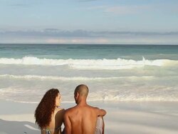 Couple sitting on sandy beach at water's edge Stock Footage