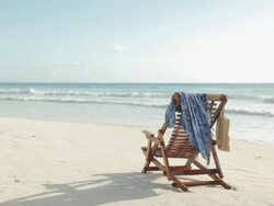 Deck chair on sandy beach at water's edge Stock Footage