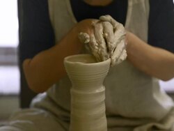 MS Shot of female potter shaping  pot from lump of clay on potters wheel at pottery / Kyoto, Japan Stock Footage