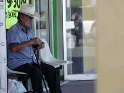 Senior man in cowboy hat sitting in front of store and waiting Stock Footage