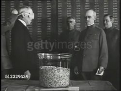 1917: WWI DRAFT LOTTERY: President Woodrow Wilson being blindfolded by officer, officer guiding hand of president into glass bowl filled w/ lottery numbers, Wilson taking out one paper, removing blindfold. Conscription, Mandatory Military Service. Instructional Video