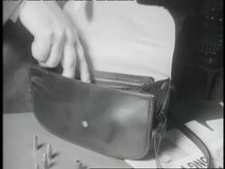 A man's hand opens a purse and takes out a Luger automatic pistol. News Clip