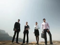 Four business people standing on the cliff of mountain Stock Footage