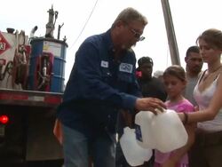 MS TD TU Shot of men filling three milk jugs with fuel from truck as people waiting in line and Hurricane Rita approaching Texas / Texas, United States Stock Footage