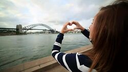 Young woman in Sydney harbour makes heart shape finger frame Stock Footage
