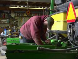 MS Shot of farmer standing and Worker working part for farm planter in garage / Chelsea Michigan Stock Footage