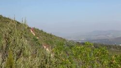 Female trail runner runs along a mountain trail above city Stock Footage