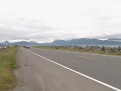 "View along busy Homer Spit Road towards snow capped mountains of Kachemak Bay State Park and Wilderness Park, Homer, Kenai Peninsula, Alaska." Stock Footage