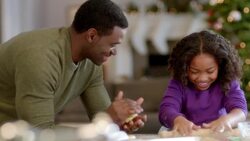 Proud father balls up dough as daughter flattens cookie dough with rolling-pin (dolly-shot) Stock Footage