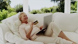 Happy senior woman shopping online on patio sofa Stock Footage