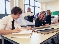 MS School Boy looking at sketchbook in art class and rest of class doing art / Bristol, United Kingdom  Stock Footage