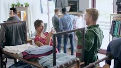 Young couple shop in local clothing store, pose for smartphone photo with striped sweater Stock Footage