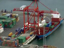Aerial wide shot pan crane unloading cargo ship at docks/ Dublin, Ireland Stock Footage