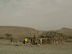 People next to hut made of wood and straw Stock Footage