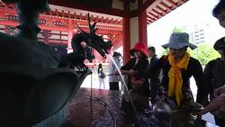 Camera captures worshippers, who are purifying themselves by washing their hands and mouth by Temizu (Purification Water) at Chozuya  (Shinto water ablution pavilion) in Sensoji Temple (Asakusa Kannon Temple). Stock Footage