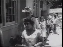 B/W 1962 line of people walking past camera outdoors / waiting for oral polio vaccine / Texas Stock Footage