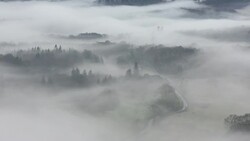 Looking down into the Langdale Valley above valley mist formed by a temperature inversion on Loughrigg, near Ambleside in the Lake District National Park, with cars driving on the Hawkshead road. Stock Footage