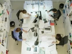 HA WS two men and two women working on  desk in modern office, one man placing phone call Stock Footage