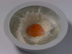 High speed Egg yolk falls into bowl of flour, top shot Stock Footage