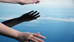 A woman uses her hands to splash water, letting it fall through her fingers which creates ripples adnd bubbles reflected in a blue sky.  Stock Footage