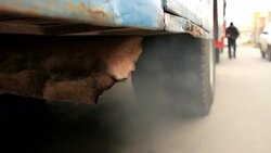 Exhaust spurts erratically from a corroded pipe under a rusty bus. Stock Footage