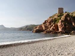 WS View of Waves at pebbles beach with genovese tower at rocky coast, UNESCO world heritage / Gulf of Porto, Corsica, France Stock Footage