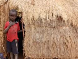 Boy by the entrance of his straw hut Stock Footage