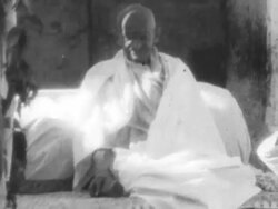 Gandhi sitting on bed in front of crowd after his release from prison Stock Footage