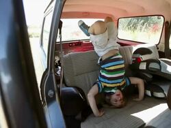 Boy standing on his head on car seat Stock Footage