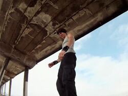 A man does a parkour freerunning backflip under a pier on the beach. - Slow Motion - Model Released - HD Stock Footage