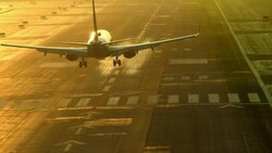 airliner passenger jet landing on airport runway at dusk creating a wavy pattern of air turbulence around aircraft Stock Footage