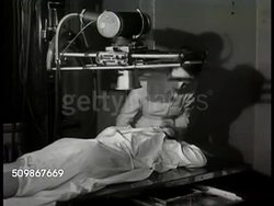 1948: HOSPITAL TESTING: CU X-Ray requisition request slip. X-Ray technician w/ 'Mrs. Conrad' reclined on stomach on table, X-Ray machine above table, techinician adjusting X-Ray machine control panel, X-Ray machine above patient. Instructional Video