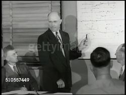 1950: SCHOOLS: EXT County Courthouse, Eureka, Illinois. REPRISING MEETING: County Survey Committee w/ people talking. CHART: Proposed schools District 140. EXT Davenport Elementary school in Eureka. INT School stairs & hallway w/ students walking. Instructional Video