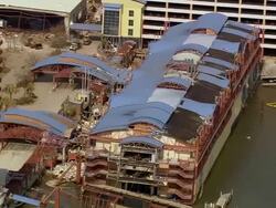 Aerial zoom in damaged blue roof of Harrah's Grand Casino during cleanup / Gulfport, Mississippi Stock Footage
