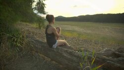 Young adult female hiker sitting on log overlooking a meadow Stock Footage