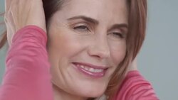 Close-up of woman 40yrs + with hair blowing in wind wearing pink Stock Footage