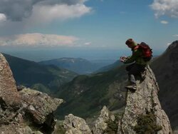 Hiker traverses rock ridge b/t pinnacles, distant mtns Stock Footage